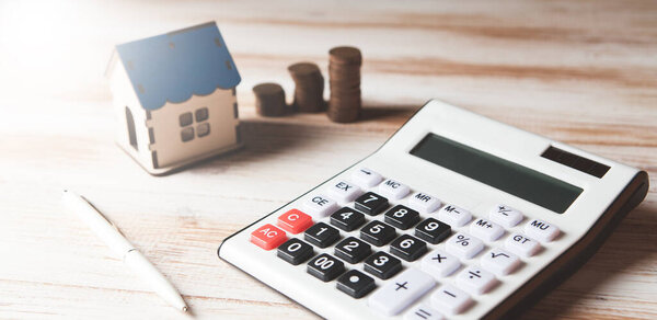 монеты, калькулятор и дом на столе