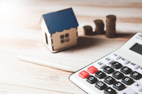 монеты, калькулятор и дом на столе