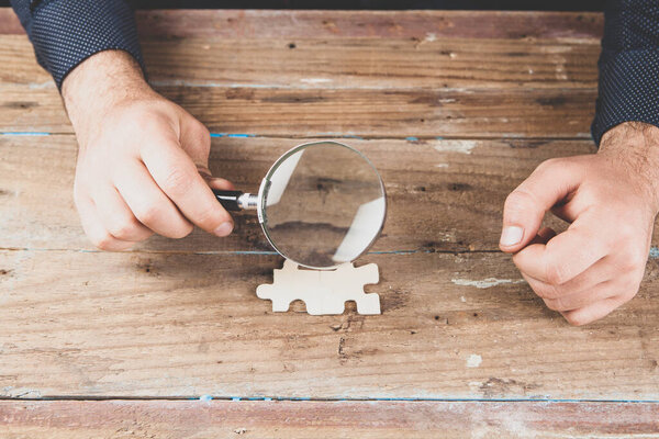magnifying glass examines puzzle pieces