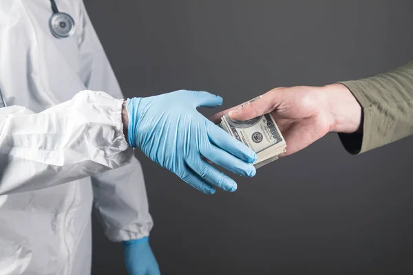 man secretly hand over money to doctor on gray background