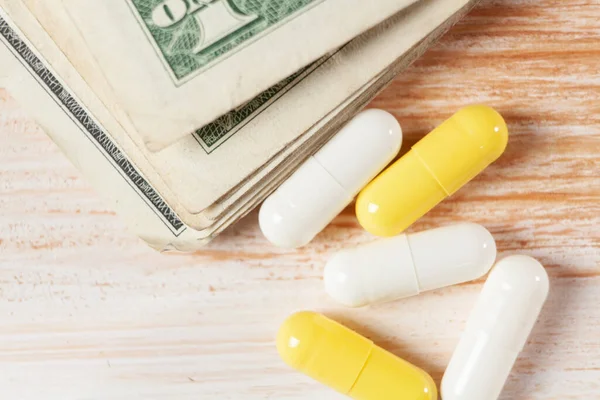 pills and money on a yellow background