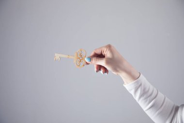 Anahtarı gri arka planda tutan genç bir kız.