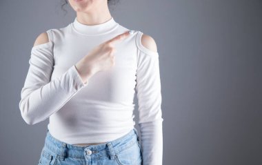 Gri arka planda genç bir kız parmaklarını kenarda tutuyor.