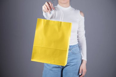 Genç kız elinde gri bir çantayla poz veriyor.