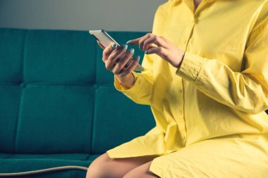 Sarı sıkışık bir genç kız telefonunu koltukta tutuyor.