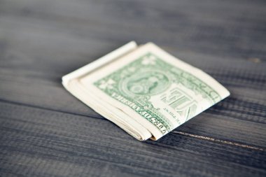 Gri ahşap bir masanın üzerinde dolar banknotları