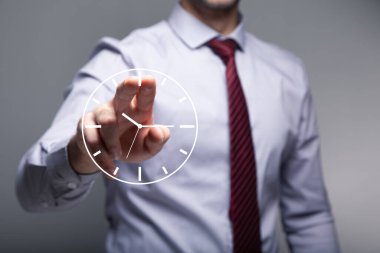 Adam gri arkaplanda sanal saate tıklıyor