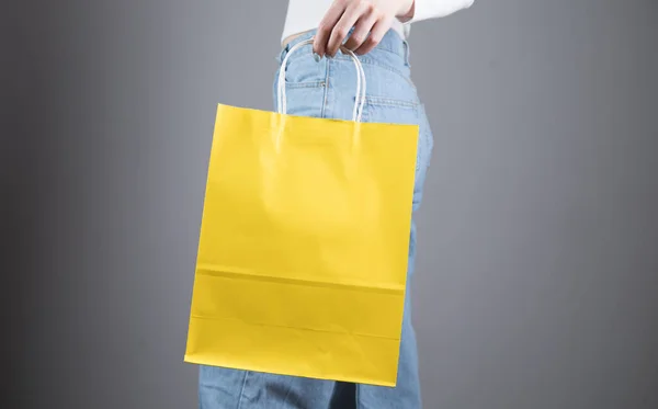 Niña Posa Sosteniendo Una Bolsa Amarilla Sobre Fondo Gris — Foto de Stock