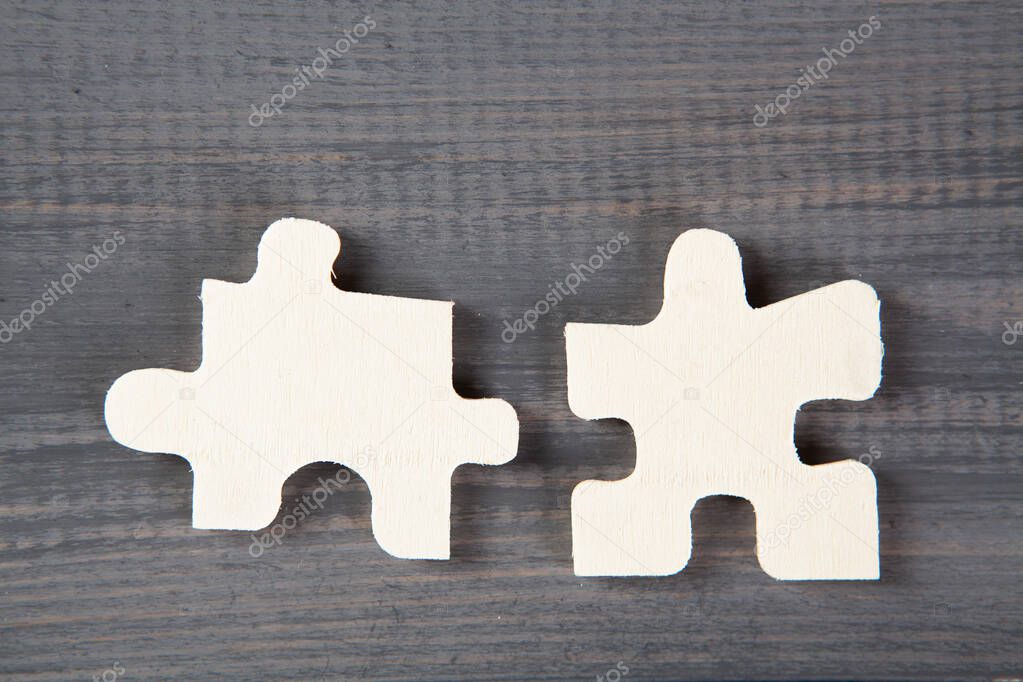 two pieces of a puzzle on a gray wooden table