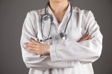 Steteskoplu bir doktor gri bir arka planda el ele tutuşur.