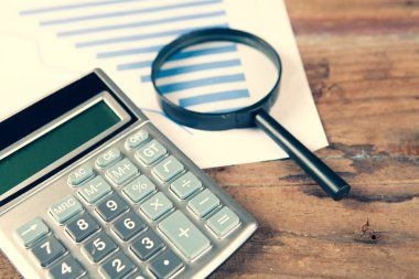 kağıt, büyüteç ve hesap makinesi masanın üzerinde