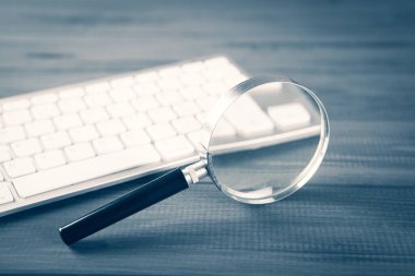 Klavye ve büyüteç. Gri ahşap masa üzerinde arama kavramı