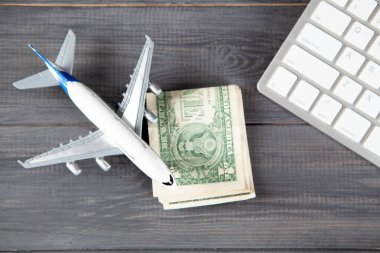 uçak, para ve klavye. Gri ahşap bir masada internet üzerinden uçak bileti almak.
