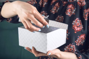 Elbiseli genç kız kanepede oturan hediye kutusunu açıyor.