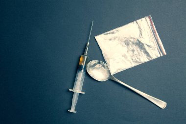 Pakette beyaz toz, siyah zemin üzerinde sıvı olan kaşık ve şırınga