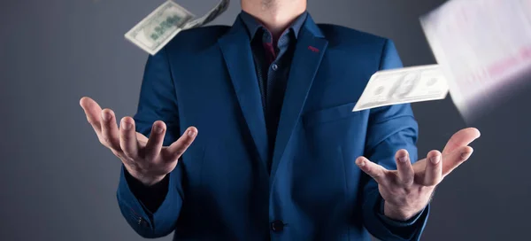 money is falling on a man in a suit on a gray background