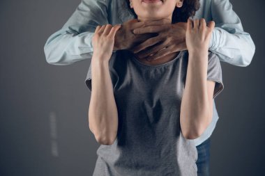 Bir adam bir kızı arkadan boğuyor.