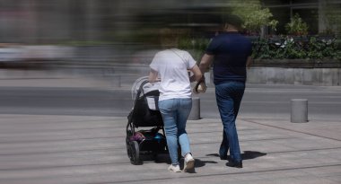 Bir çift şehirde bebek arabasıyla geziyor.