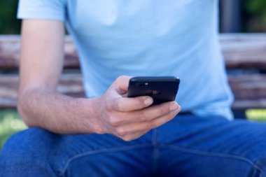 Sokakta genç bir adam telefonda oturuyor.