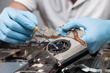 Adamın biri gri arka planda bir dizüstü bilgisayarı parçalara ayırıyor.