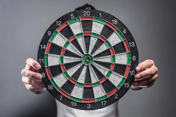 Gri arka planda dart tahtası tutan adam
