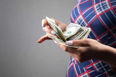 Genç kadın gri arka planda para sayıyor.