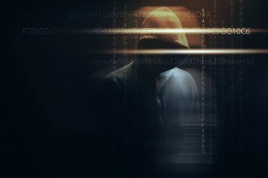 Kapüşonlu bir adam siyah arka planda duruyor.