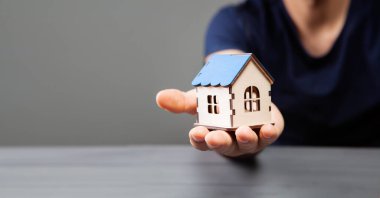 Elinde bir ev tutuyordu.