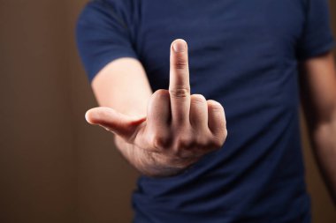 Kahverengi arka planda orta parmağını gösteren bir adam