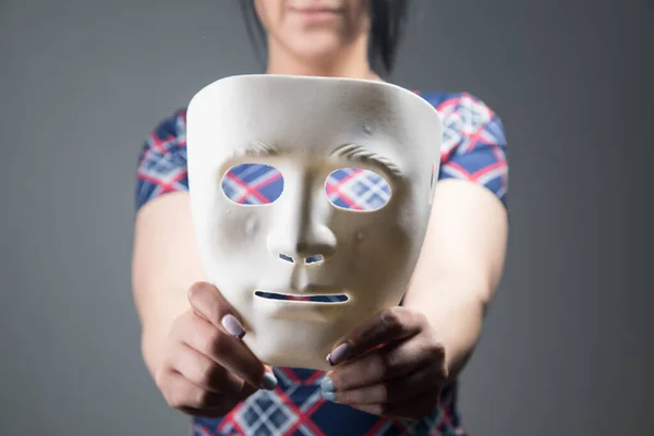 woman holding white plastic mask on gray background