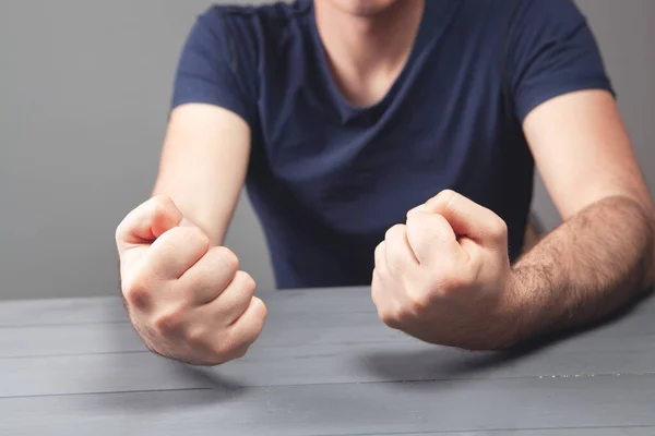 hits the table with his fist on a gray background