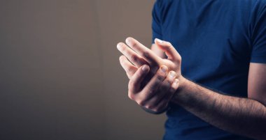 Genç adamın kahverengi arka planda yaralı bir kolu var.