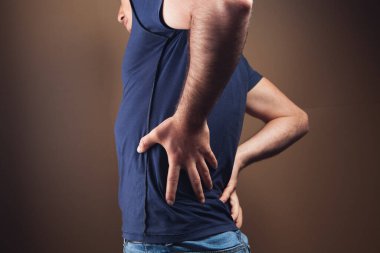 Bir adam kahverengi arka planda böbreklerine zarar verir.