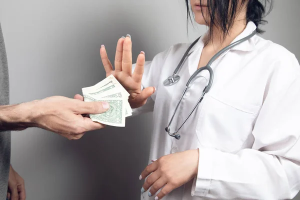 doctor refuses to accept money on gray background