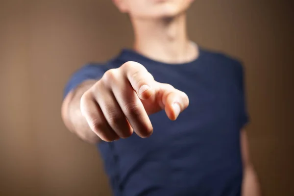 young guy points his finger at a brown background