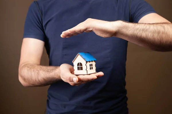 protects the house with his hands on a brown background