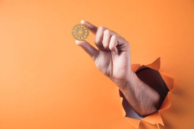 El, turuncu arka planda vites tutuyor