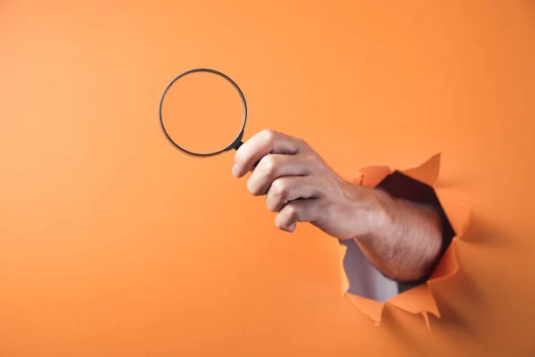 Hand Holding Magnifying Glass Orange Background — Stock Photo, Image