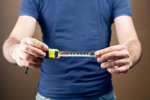 stock image a man holds a centimeter in his hands and measures a penis on a brown background