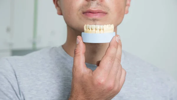 a man holding a mock jaw at the dentist