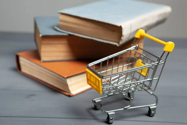 cart and books on the table. concept of buying books on gray background