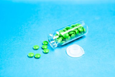 Mavi bir masanın üzerindeki mataradan yayılmış haplar.