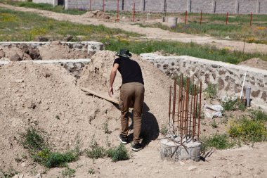 Bir adam tek katlı bir evin inşaatında çalışıyor.