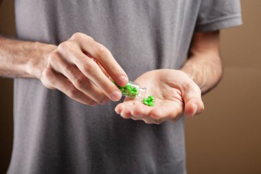 Kahverengi arka planda hapları olan kapsülü tutan adam.