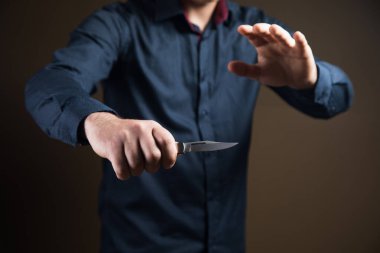 Kahverengi arka planda el bıçağı tutan adam.