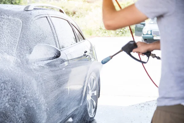 Yüksek basınçlı hortumu olan bir adam köpük sürer.