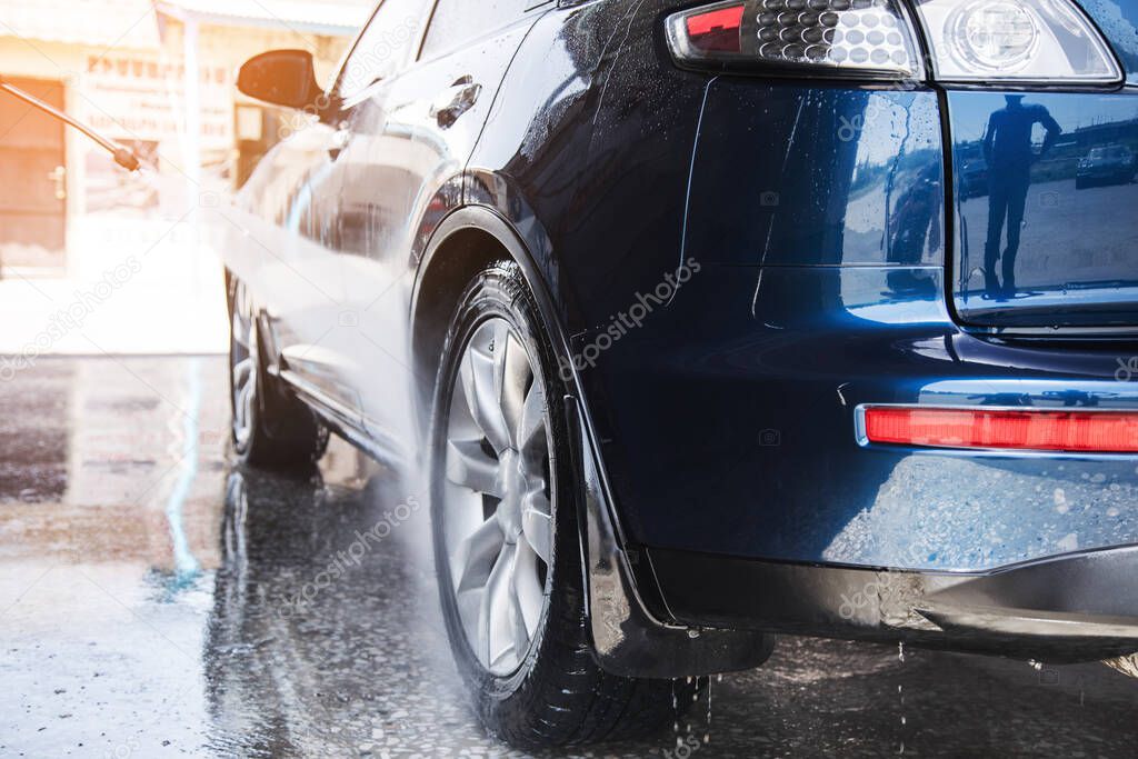 a man washes his car with water