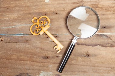 Anahtarlar ve büyüteç ahşap bir masada.