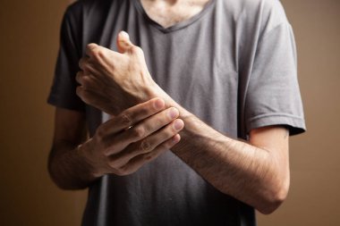 Kahverengi arka planda bir adamın eli acıyor.