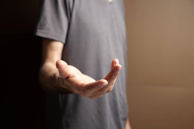 Adam kahverengi arka planda açık avuç içi gösteriyor